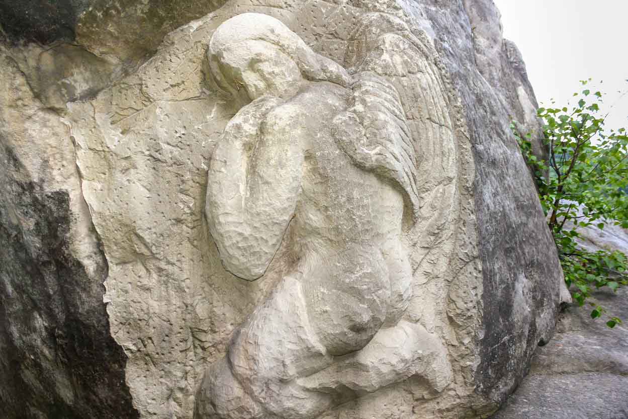 Stone Carving Ancient Faces Into Cliff